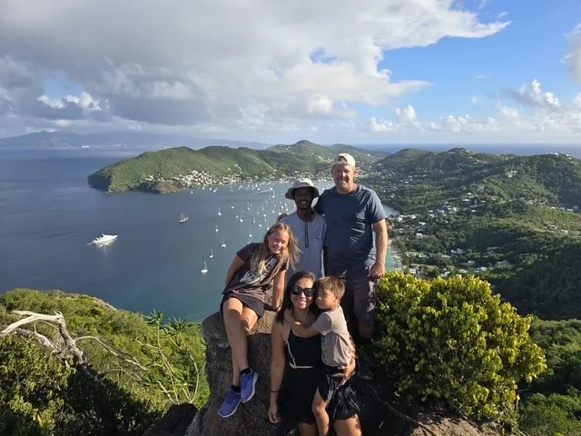 Guests on a hilltop above a bay full of anchored yachts